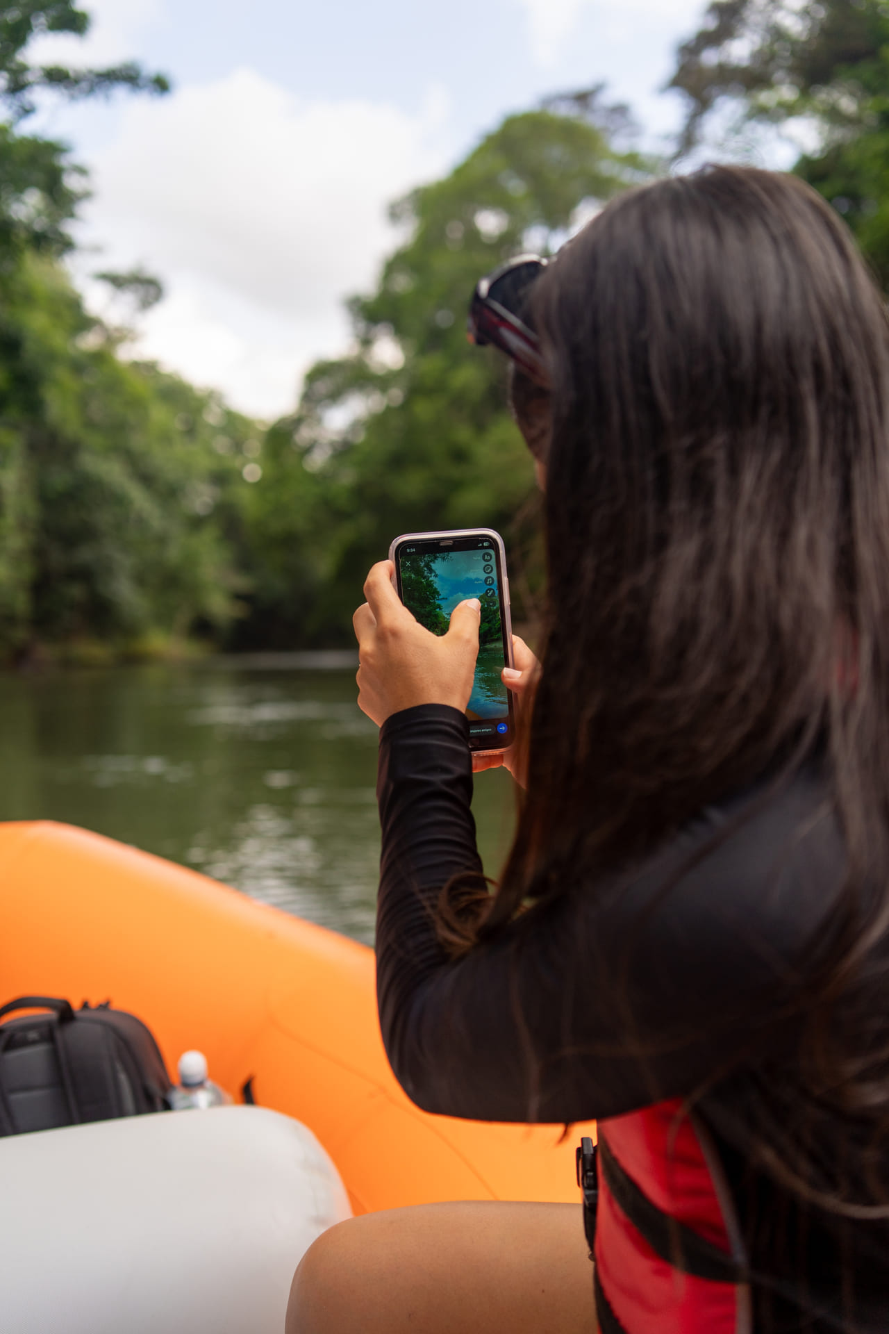 Invitada fotografiando el río con su celular en funda waterproof desde la balsa