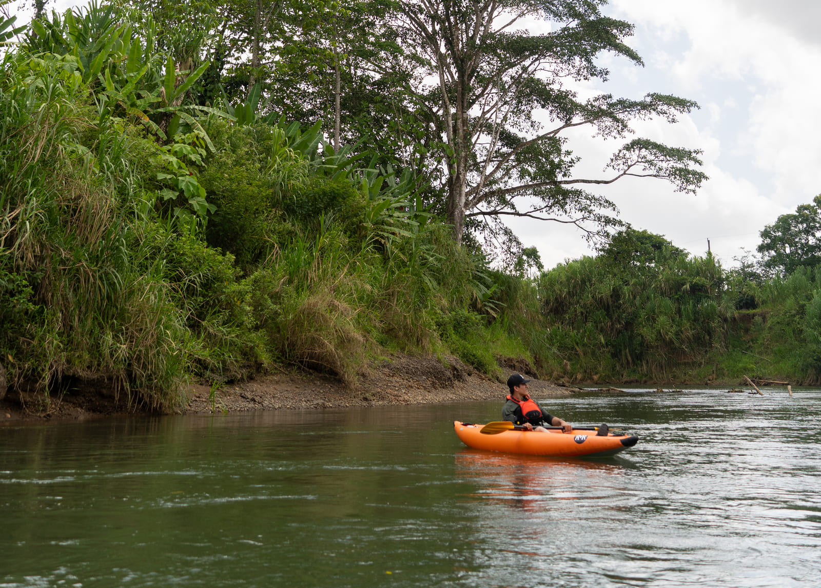 Kayakista en kayak inflable naranja deslizándose solo por el ancho del Río Peñas Blancas